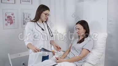 年轻的女医生在医院病房里和一个看x光的病人交谈。 医生来<strong>看病</strong>人
